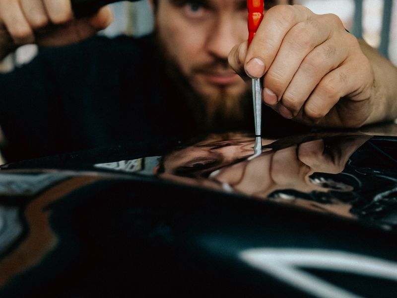 Technician removing a dent from a car body panel