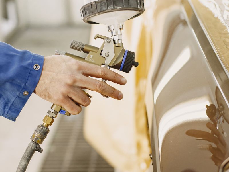 Spray painting a car panel in a paint booth